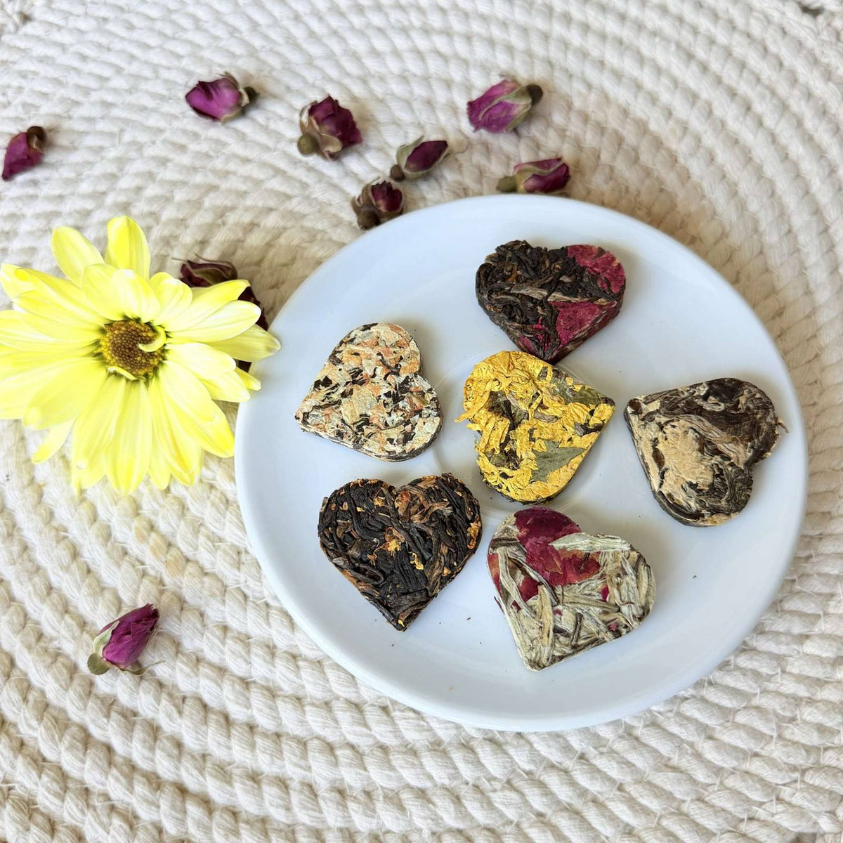 Close view of seven compressed tea hearts showing whole tea leaves and real flowers pressed into each heart