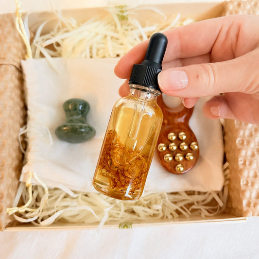 Hand holding a dropper bottle of calendula-infused botanical oil for scalp care