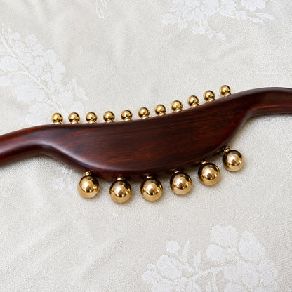 Close-up of 17 solid brass massage beads — 11 small and 6 large — on the wood massage wand