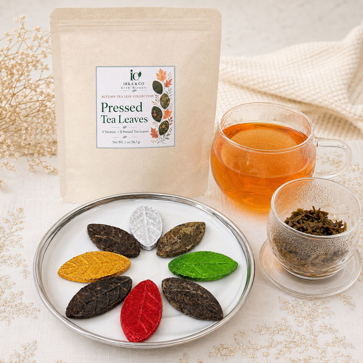 Autumn Tea Leaf Collection pouch beside a plate of pressed tea leaves, a cup of tea and opened leaves in a glass