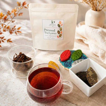 Kraft pouch of pressed tea leaves with a glass cup of brewed tea and colorful leaf-shaped teas on an autumn table