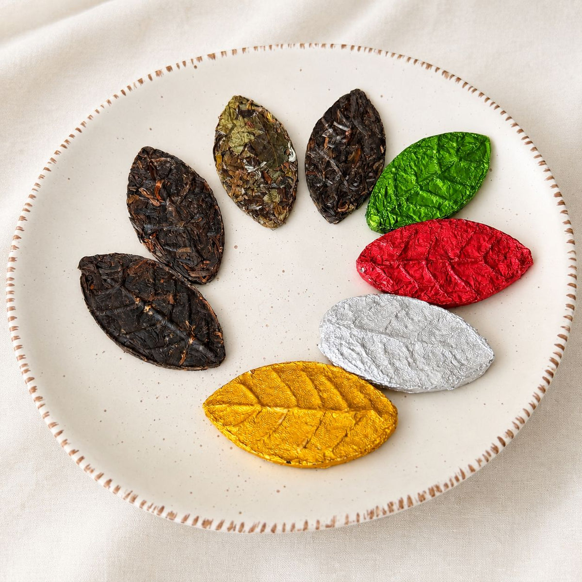 Pressed tea leaves in autumn colors arranged on a white ceramic plate