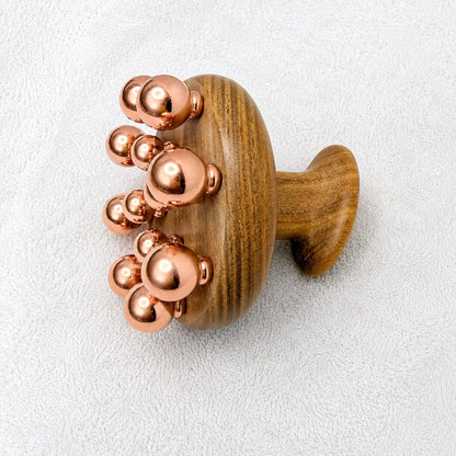 Angled view of the copper ball cluster on the green sandalwood massage tool