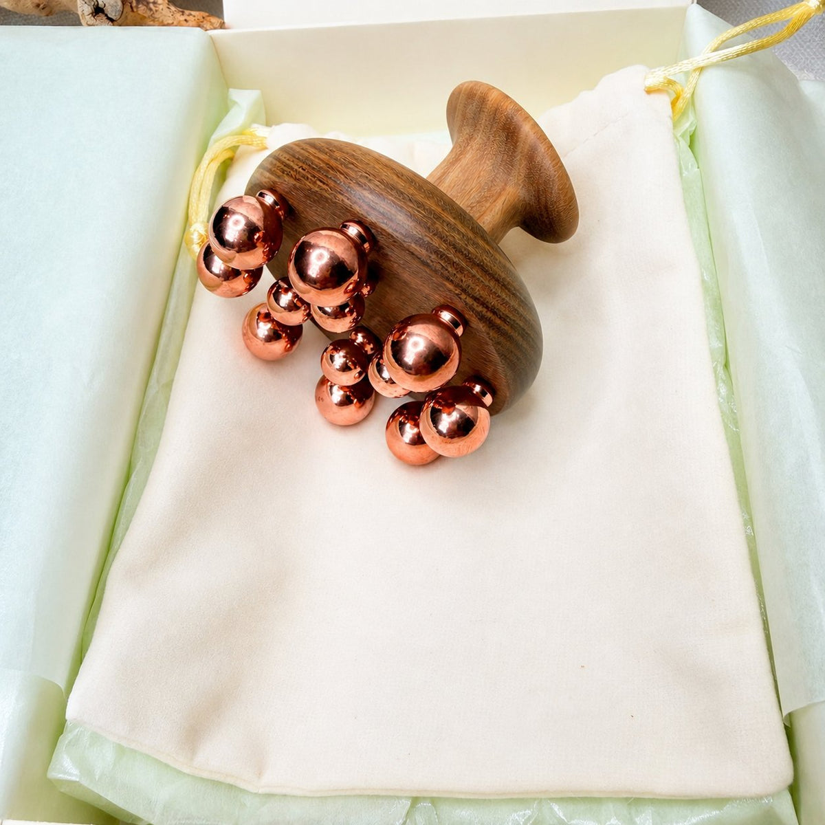 Copper cluster massage tool resting on its cotton pouch inside the Irka & Co gift box