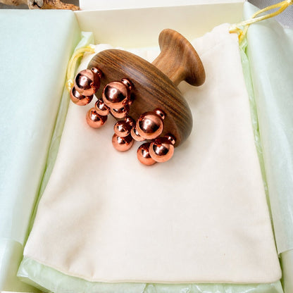 Copper cluster massage tool resting on its cotton pouch inside the Irka & Co gift box