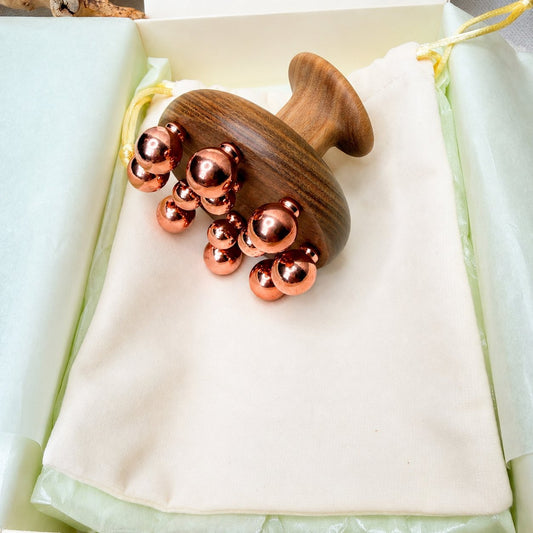 Copper cluster massage tool resting on its cotton pouch inside the Irka & Co gift box