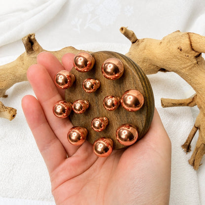 Copper cluster massage tool held in an open palm to show its size