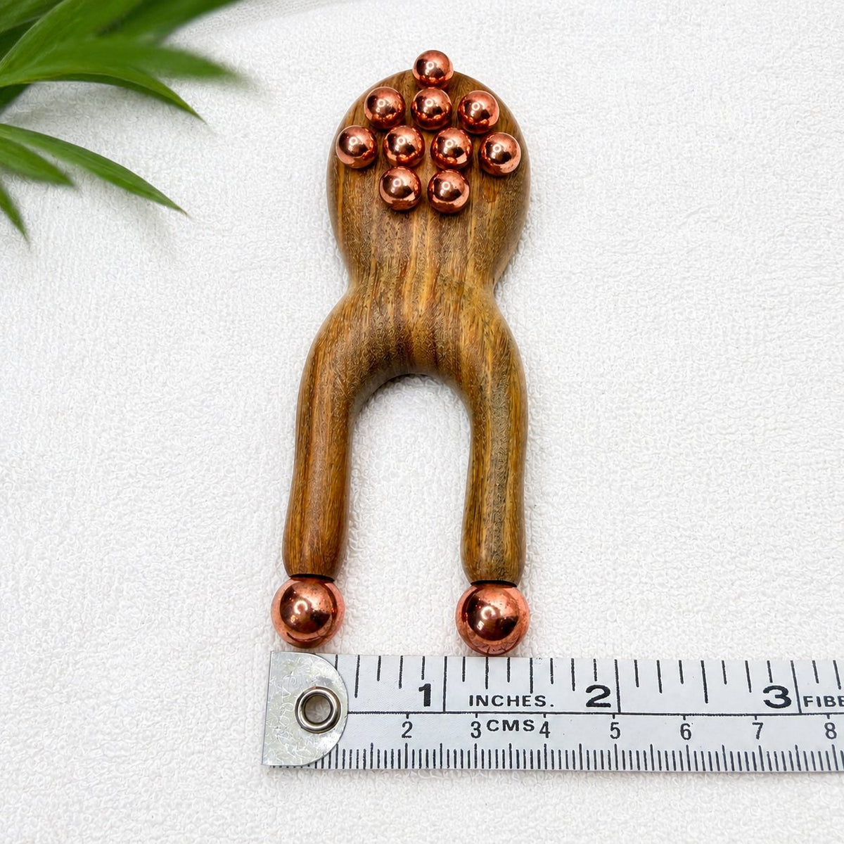 Green sandalwood facial lift massager shown upright next to a ruler measuring 4 inches long