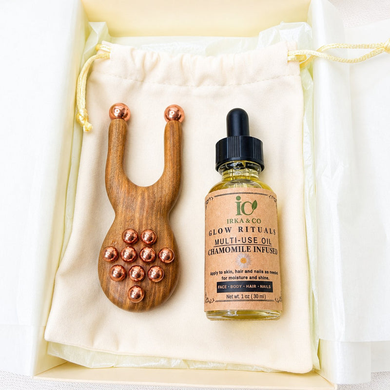 Gift box open to show the facial lift massager with a botanical facial oil bottle tucked inside
