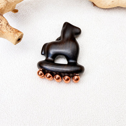 Copper & Purple Sandalwood Little Horse facial massage tool resting on driftwood against a white textured background
