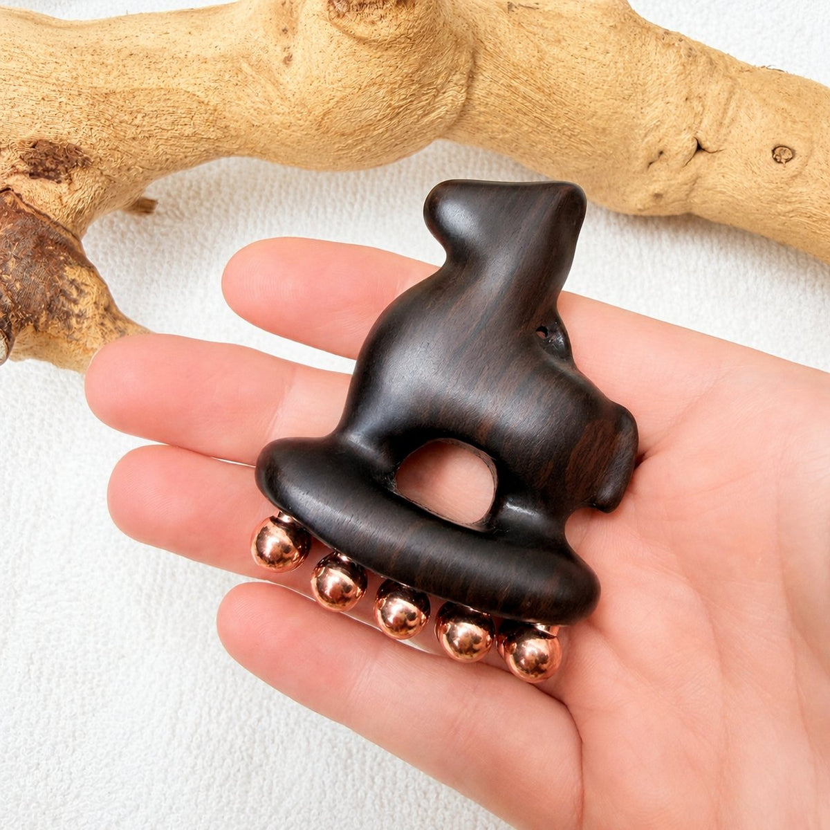 Copper and purple sandalwood Little Horse tool held in an open palm to show its pocket-sized scale