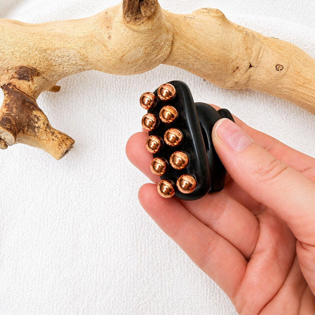 Side view of the Little Horse tool in hand showing the two rows of copper massage balls