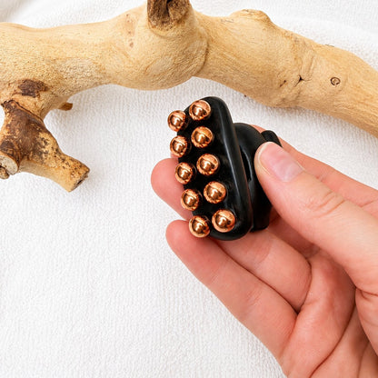 Side view of the Little Horse tool in hand showing the two rows of copper massage balls