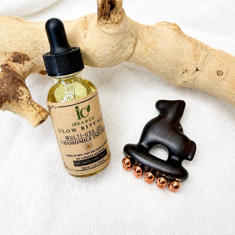 Little Horse facial massage tool and Glow Rituals Chamomile oil bottle on driftwood, overhead flat lay