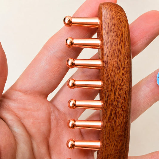 Close-up of the rounded copper teeth of the scalp and body ritual comb held in hand