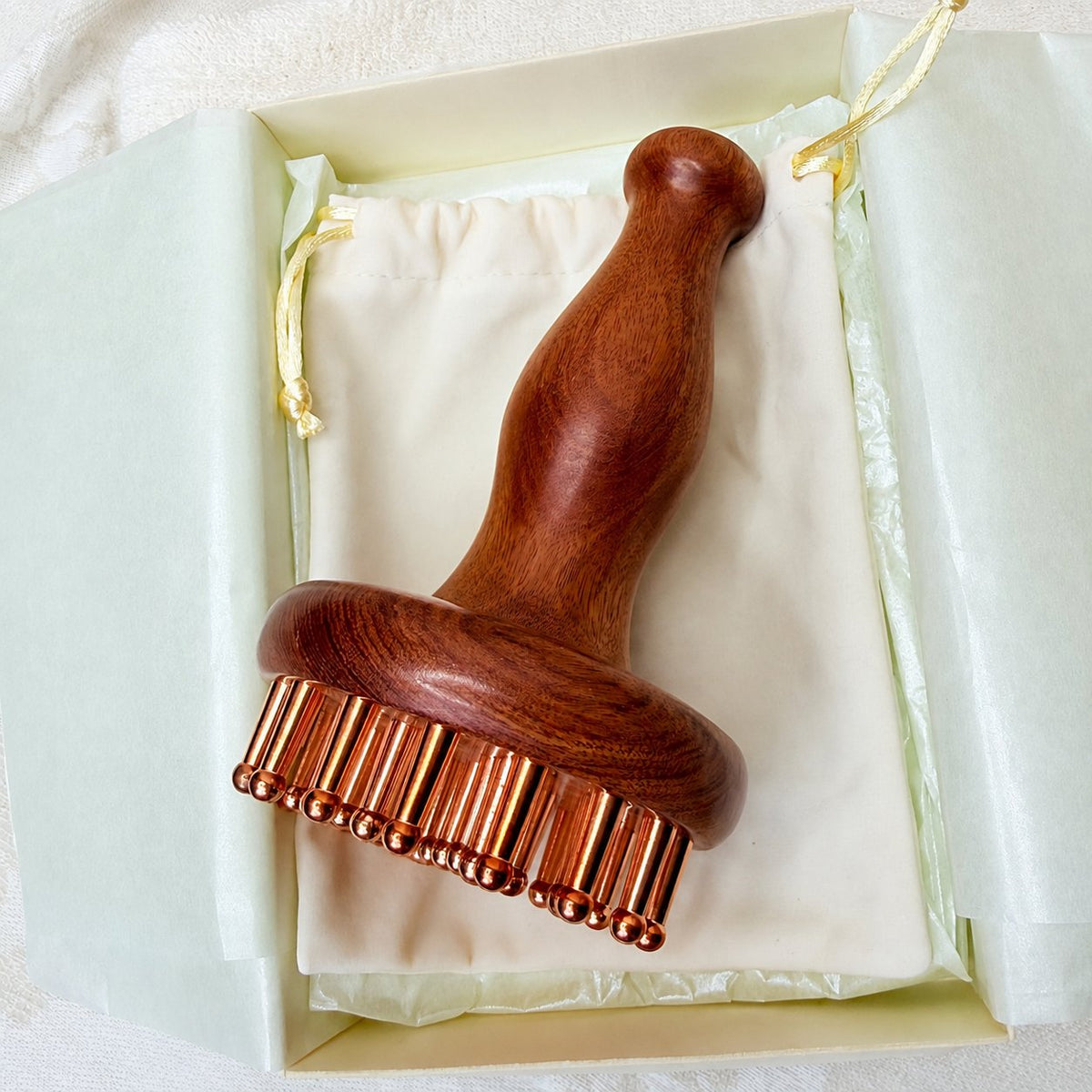 Copper & Rosewood Deep Tissue Massager lying in its gift box with cotton pouch, copper teeth visible