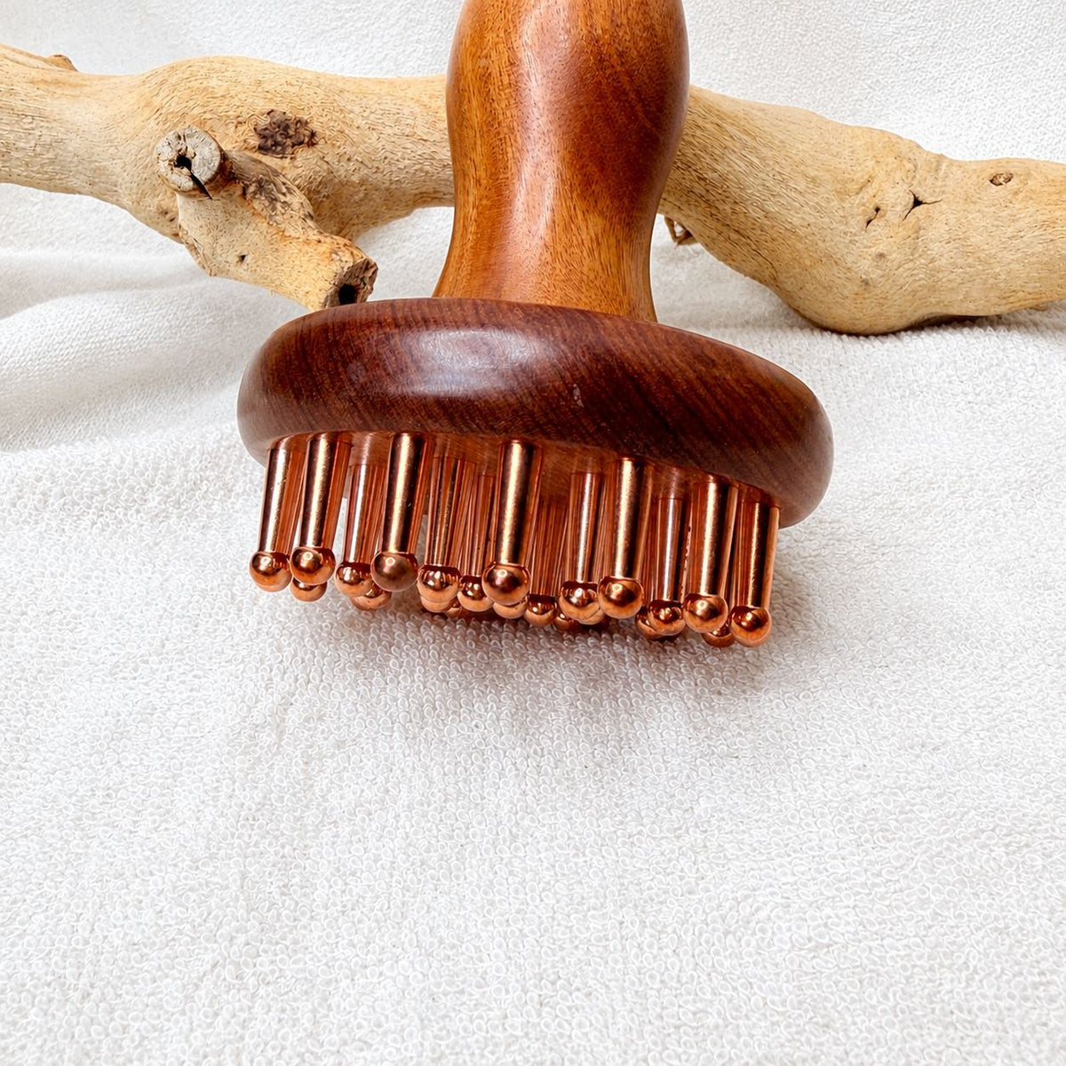 Front view of the Copper & Rosewood Deep Tissue Massager standing upright against driftwood