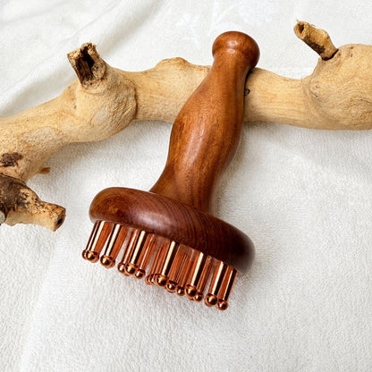 Copper & Rosewood Deep Tissue Massager resting on driftwood, handle upright