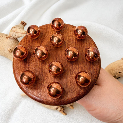 Close-up of the copper bead cluster head of the body contouring massage tool held in hand