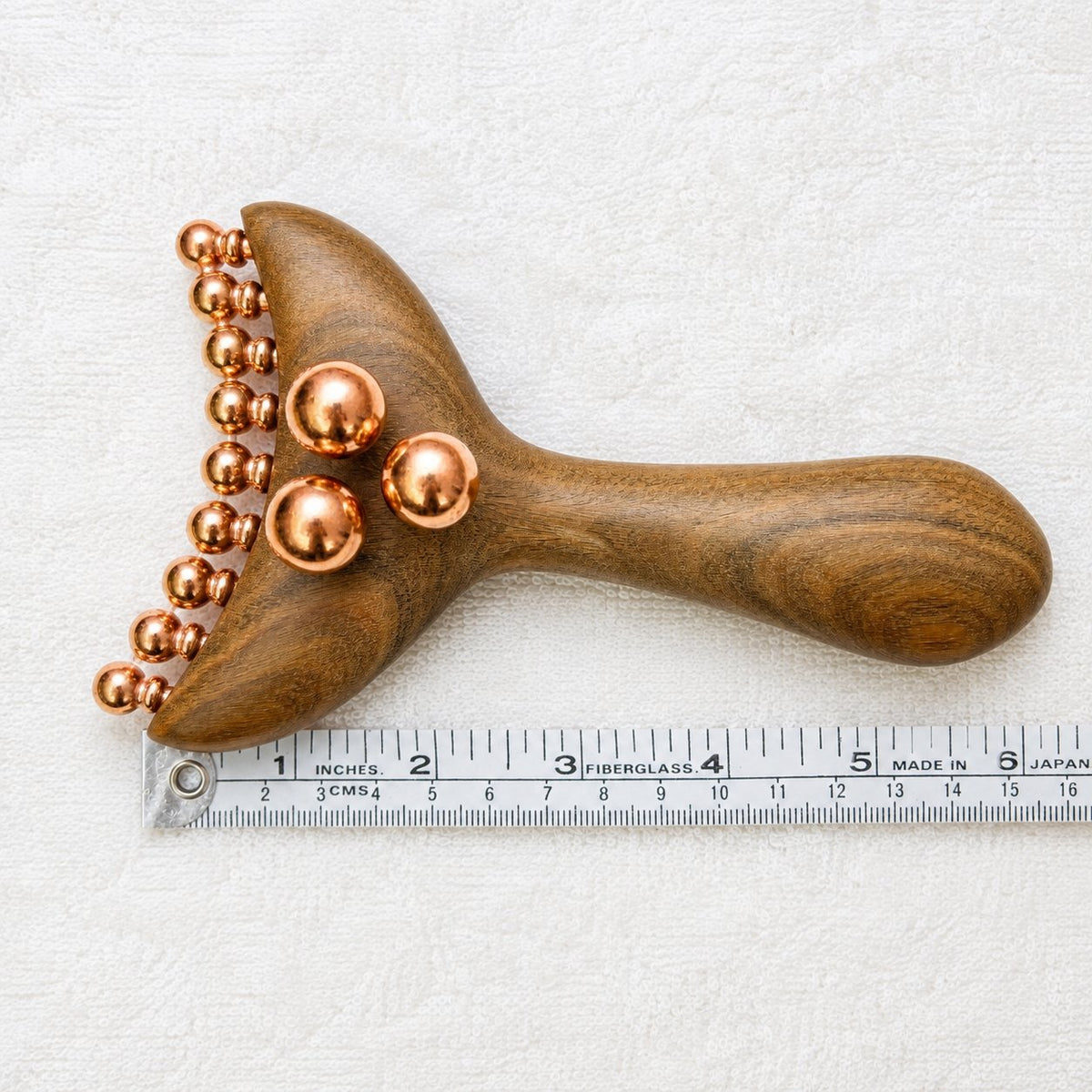 Copper & Wood Deep Tissue Massage Tool for Shoulders & Glutes shown flat next to a ruler, measuring about 6 inches long with its full row of copper massage balls visible