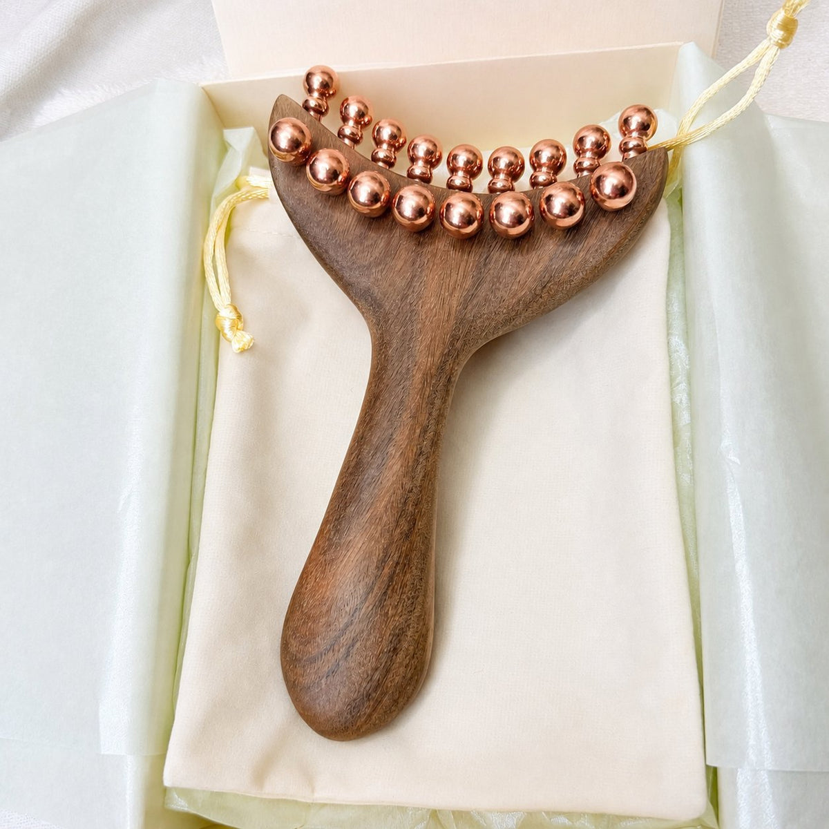 Top-down close-up of the Copper & Wood Deep Tissue Massage Tool in its gift box, showing the full double row of copper massage balls