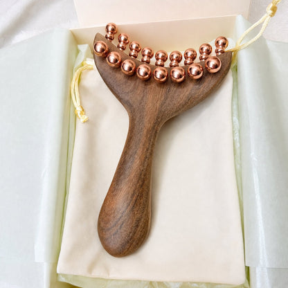 Top-down close-up of the Copper & Wood Deep Tissue Massage Tool in its gift box, showing the full double row of copper massage balls