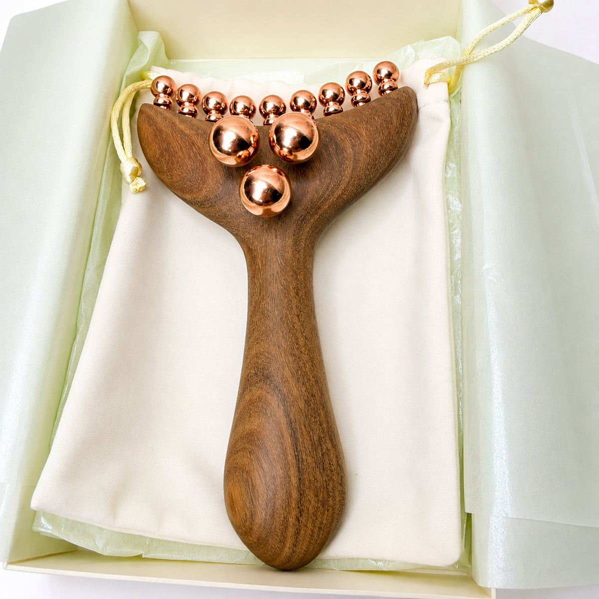 Close-up top-down view of the Copper & Wood Deep Tissue Massage Tool in its gift box, highlighting the full copper ball cluster and curved bead row