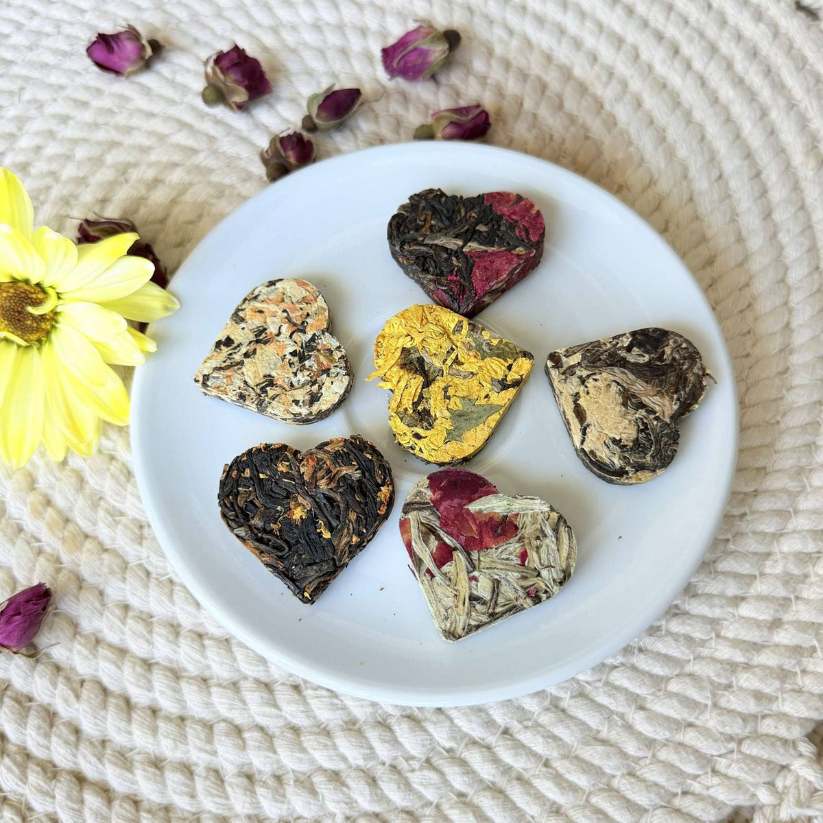 Assorted tea hearts in black, yellow and floral tones on a small white plate — a tea lover gift ready for brewing