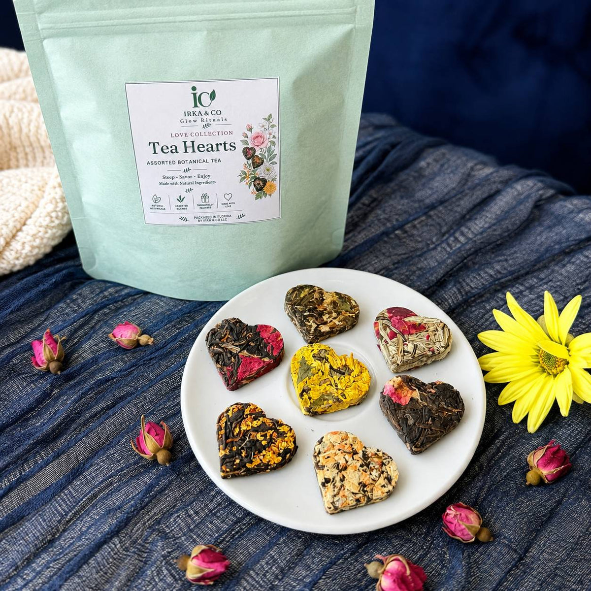 Tea Hearts gift set styled with the Irka & Co pouch, seven tea hearts on a plate, rose buds and a yellow flower