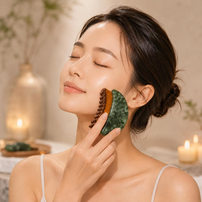 Woman with eyes closed using the jade comb gua sha tool on her cheek in a candlelit spa setting