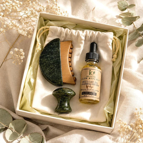 Close-up top-down view of the Jade Gua Sha & Scalp Ritual Set with gua sha, comb, mushroom roller, and Calendula Infused Oil in the gift box, styled with eucalyptus and dried baby's breath