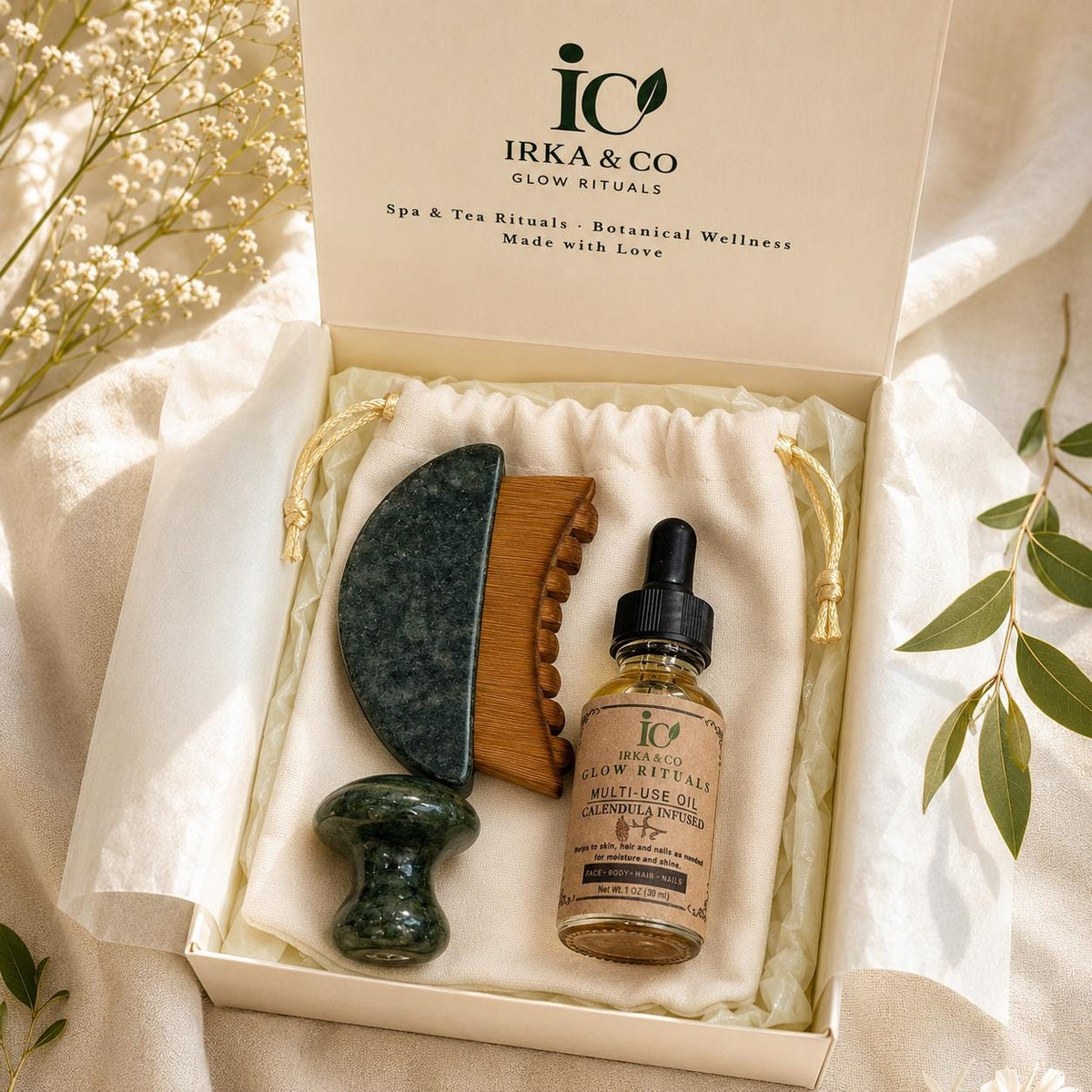 Jade Gua Sha & Scalp Ritual Set gift box with the IRKA & CO branded lid open, styled with eucalyptus and baby's breath