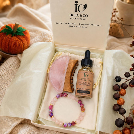 Rose Quartz Ritual Set with gua sha, wooden comb, Rose Infused Multi-Use Oil, and beaded bracelet in an open IRKA & CO gift box styled with autumn decor
