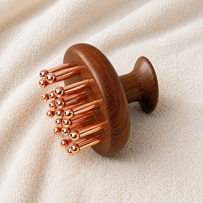 Copper & Sandalwood Scalp Massage Comb on a textured cream towel, angled view showing the round wooden head with copper prongs and mushroom-shaped handle