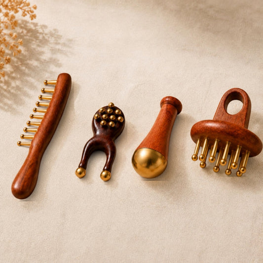 Four Irka and Co. massage tools turned from wood and tipped with solid brass, laid out on a warm beige ground